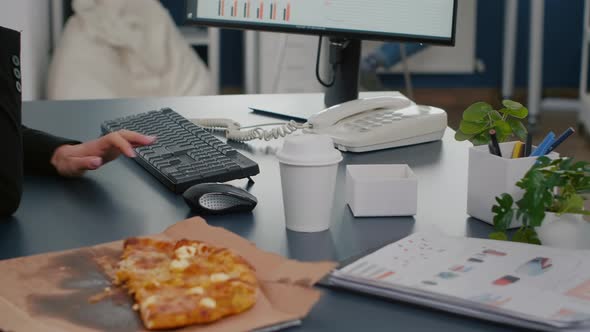 Closeup of Businesswoman Sitting at Desk in Front of Computer Eating Pizza Slice