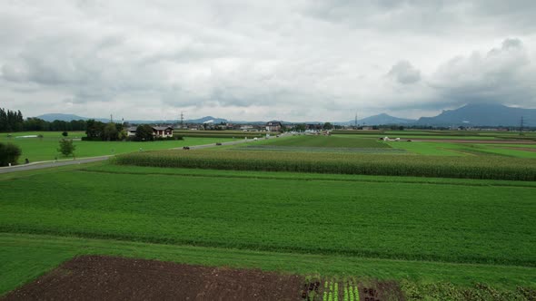 Aerial View of Green Agricultural Fields in Austria Near the Mountains in Clouds