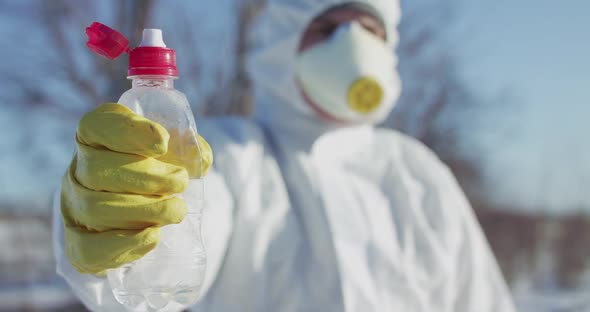 Man in Protective Costume and Glove Constricts Plastic Bottle