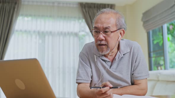 Home office of Asian Senior elderly business man working online with laptop computer at home.