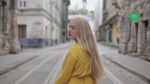 Backside View of Young Woman with Long Blond Hair Walking at Old City Street. Beautiful Female