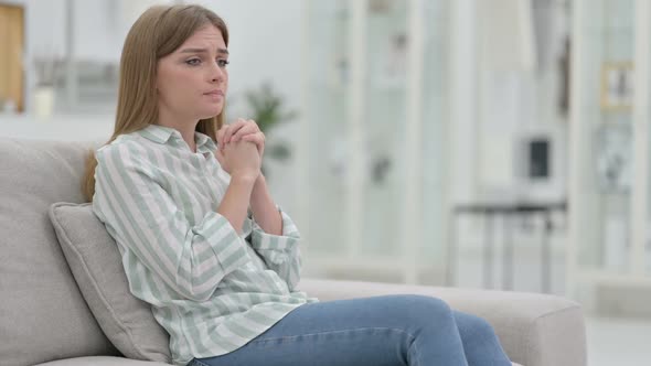 Worried Young Woman Sitting on Sofa and Thinking