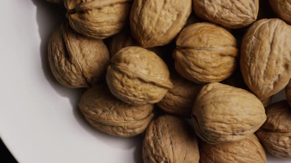 Cinematic, rotating shot of walnuts in their shells on a white surface - WALNUTS 050