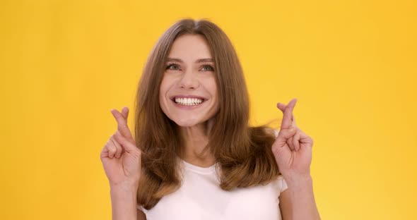 Young Positive Woman Crossing Fingers Making Cherished Wish Smiling Orange Studio Background