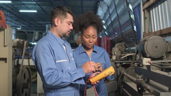 Two professional engineers inspect machines' electric systems at the factory.