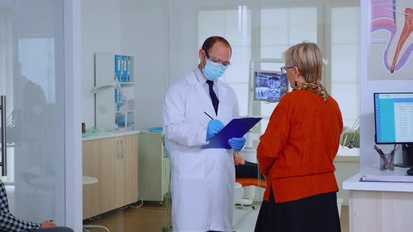 Orthodontist with Mask Speaking with Elderly Woman in Waiting Area