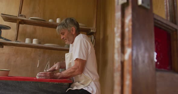 Senior caucasian man wearing apron making pottery in his workshop