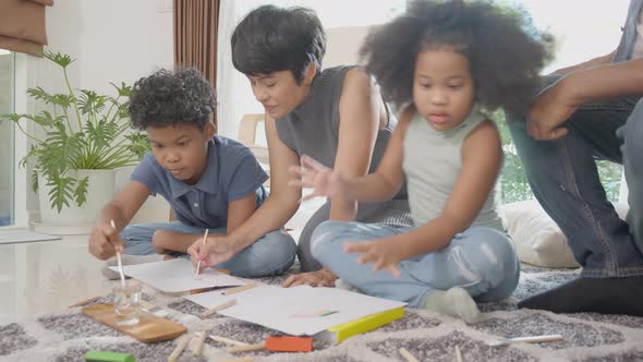 Happiness family with father and mother looking children drawing with colorful pencils.