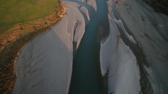 Aerial pan up over New Zealand alpine river to snow capped mountains