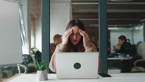 Attractive Sad and Depressed Caucasian Female Reading News on Her Laptop Computer