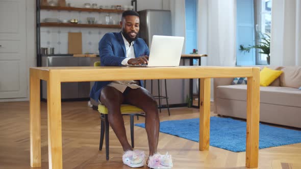 Young African Man Working at Home on Laptop Wearing Jacket and No Pants