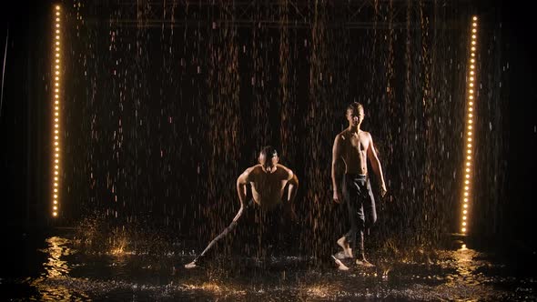 Performance By Two Acrobats in the Rain. Men Do Handstands and Balance in Slow Motion