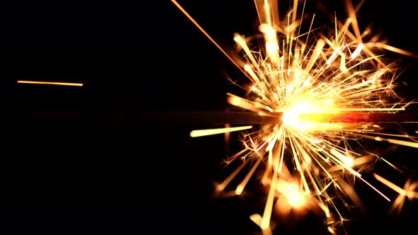 Burning sparkler on black background, vertical video