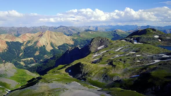 Aerial View of Drone Flying Up Over a Mountain Toward Snow Patches In The Mountain Tops