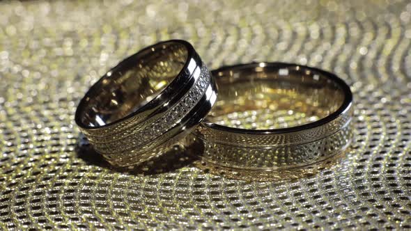 Wedding Gold Rings Lying on Shiny Glossy Surface, Shining with Light, Close-up