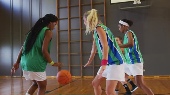 Diverse female basketball team playing match, dribbling and shooting ball