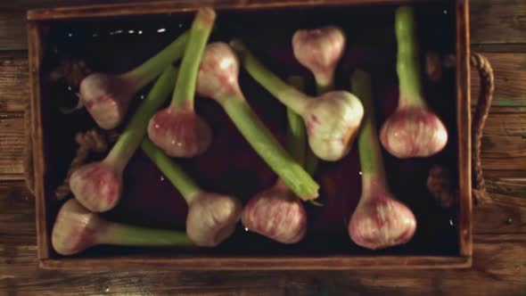 Super Slow Motion Tray with Garlic Falls on a Wooden Table