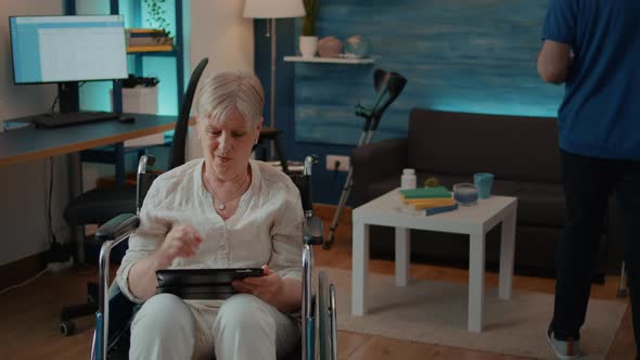 Retired Person Using Digital Tablet and Sitting in Wheelchair