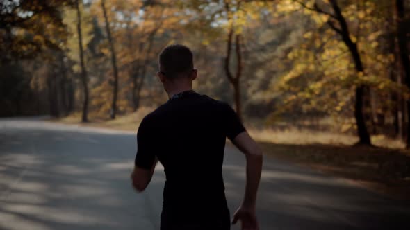 Runner Man In Sportswear Preparing To Triathlon And Sprinting In Park On Fall. Running Man On Road.