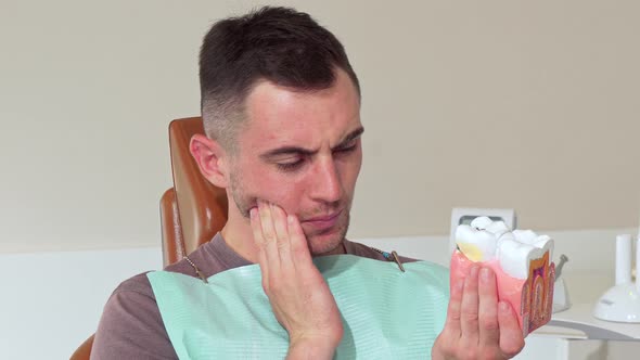 Young Man Having Toothache, Sitting in a Dental Chair at the Clinic