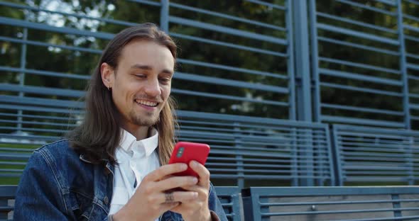 Crop View of Happy Millennial Guy with Long Hair Laughing While Using Smartphone, Bearded Young Man