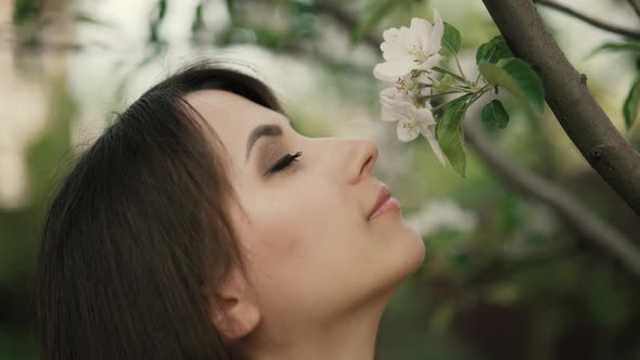 Young Woman Sniffing Flowers on a Tree