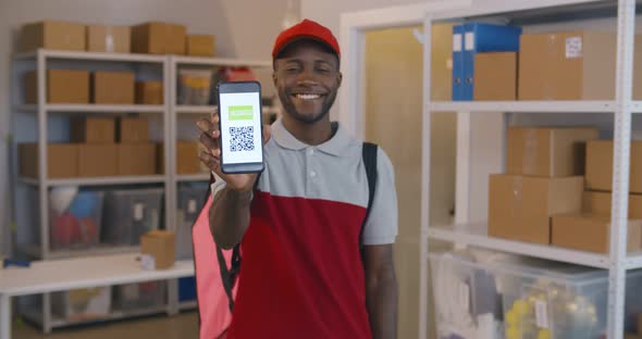 Happy Afroamerican Deliveryman Smiling at Camera Showing Cellphone with Vaccinated Qrcode