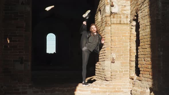 Beautiful athletic woman with a tough stretch doing splits standing up in an abandoned building