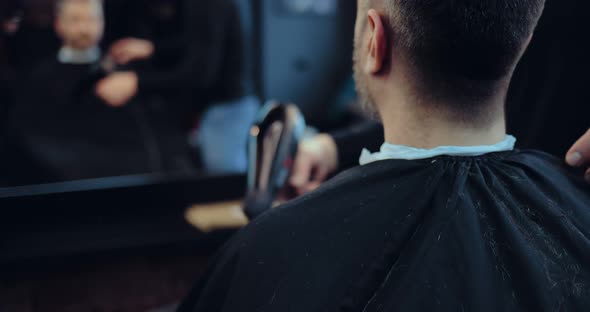 Hairdresser Blows Off Hair From the Client’s Cape
