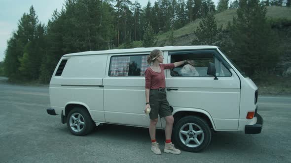 Woman Standing by Van and Petting Dog