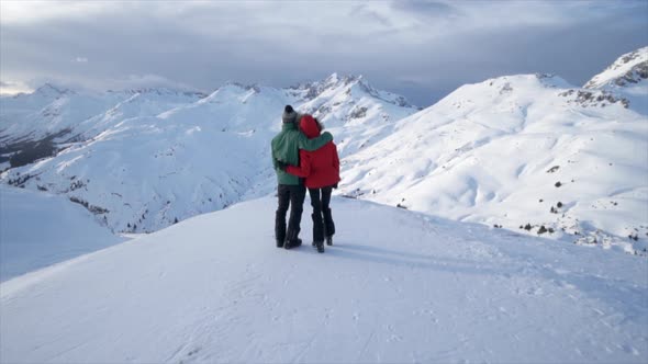 A man and woman couple standing on top of a mountain lifestyle in the snow winter