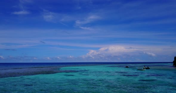 Wide fly over island view of a white sand paradise beach and blue sea background in 4K