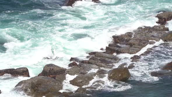 Beautiful blue ocean waves crashing the rocky shore.