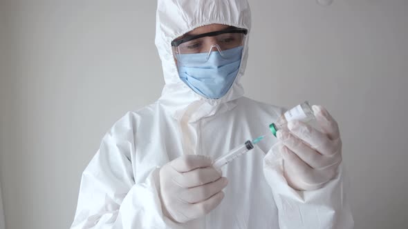 Masked gloved doctor pours coronavirus vaccine into syringe