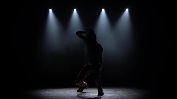 Silhouette Guy Performs Modern Hip Hop Dance on the Dark Studio with Smoke and Lighting, Twisting