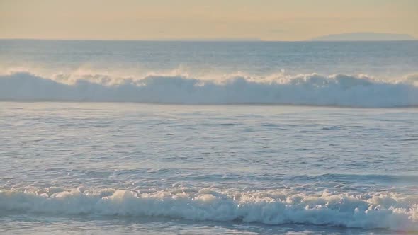 Oean waves crashing near the shoreline, on a sunny evening