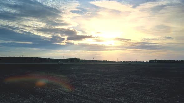 Sunset Sun From Behind Clouds Above Dark Field and Road