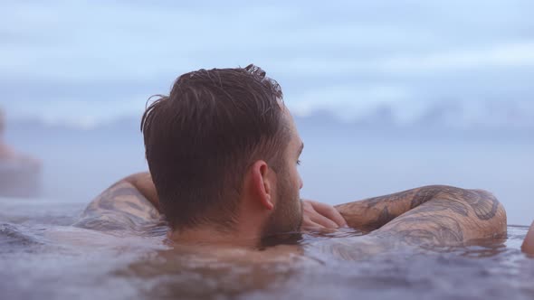 Tattooed Man Soaked in Water With Tranquil Scene of SnowCapped Mountains