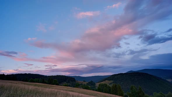 Colorful clouds at sunset over the hilly and forest landscape in the Carpathian hills