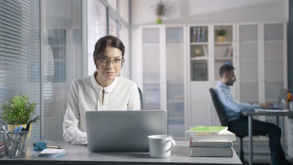 Attractive Sexy Business Woman in Glasses Creates a Presentation and Writes Information in Laptop