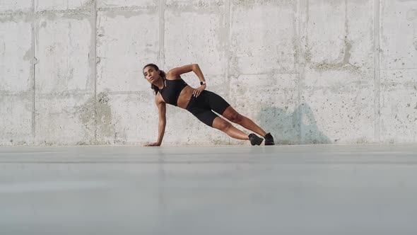 A focused african american woman doing side plank outside