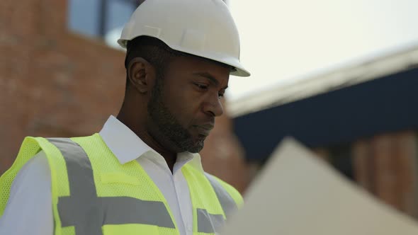 Architect with Blueprint Paper at House Construction Site