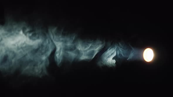 A Flashlight Beam Illuminates the Smoke on a Black Background