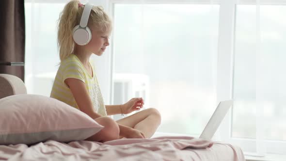 Blonde Schoolgirl Studying on Bed at Home Doing School Homework with Laptop