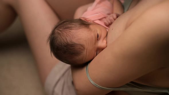 Close-up of newborn baby being milked by a young mother