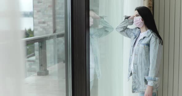 Confused Girl in Mask From Virus Comes to Glass Door Leans on It and Thinks