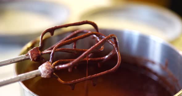 Delicious vegan chocolate cake batter dripping from electric mixer into a mixing bowl while baking d