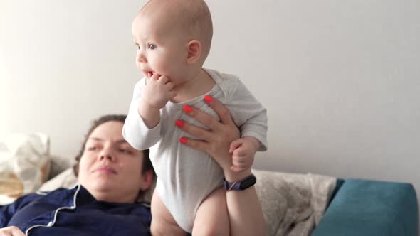 Mother Plays with Her Baby at Home on Her Lap