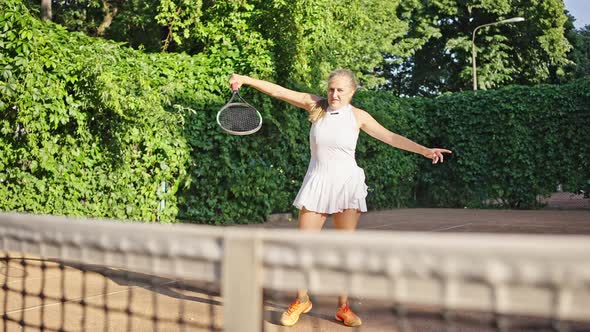 Woman in White Dress Hits Ball Serve on Tennis Court Closeup