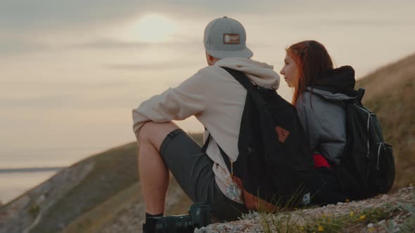 A Guy and a Girl are Sitting on Top of a Mountain and Enjoying the Landscape